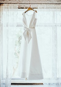 Wedding dress hanging by window, aesthetic photo