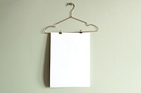 Blank poster hanging on cloth hanger, green wall