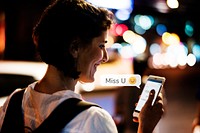 Happy woman texting while walking at night