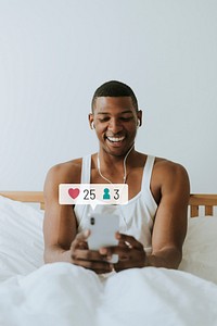 Happy man using social media on his smartphone while in bed