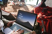 Woman using a laptop screen mockup at a camping trip