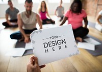 Yoga instructor holding a paper mockup in the class