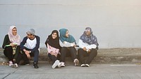 Happy muslim women sitting together outdoors