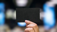 Hand holding a black paper card website banner template