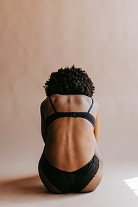 Half-naked woman sitting on a floor, rear view