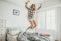 Happy blond girl jumping on the bed