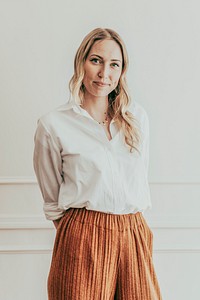 Confident woman standing by a white wall