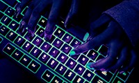 Woman typing on glowing keyboard at night