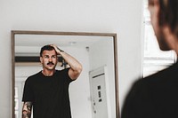 Fashionable man looking at himself in the mirror