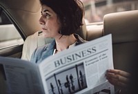 Businesswoman reading newspaper in a car