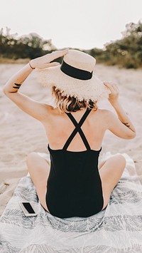 Tanned girl in a black swimsuit at the beach, rear view
