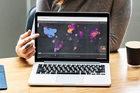 Woman showing confirmed cases of Covid-19 for countries across the globe  from a laptop mockup with editorial graphic from <a href="https://www.healthmap.org/covid-19" target="_blank">https://www.healthmap.org/covid-19</a> accessed on April 8th 2020. BANGKOK, THAILAND - MARCH 28, 2018