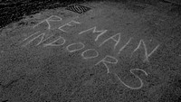 Remain indoors written in chalk on the asphalt road