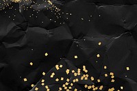 Gold glitter on a crumpled black paper background