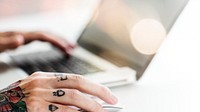 Tattooed hand using a laptop