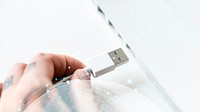 Hand connecting a USB cable to a laptop
