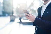 Businessman using his phone in a city