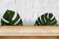 Wooden table with leaves on a white brick wall product background