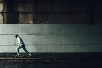 Man skateboarding under a bridge with urban wall