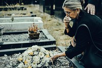 Old woman laying flowers on a grave