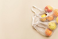 Oranges in mesh bag with design space on beige background