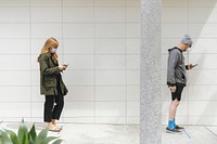 People using their phones and having social distancing while line up during coronavirus pandemic. Los Angeles, USA, April 4, 2020