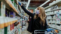 Woman in a face mask wearing latex gloves while shopping in a supermarket during coronavirus quarantine