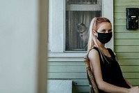 Girl wearing a mask sitting on her porch during the coronavirus lockdown. 