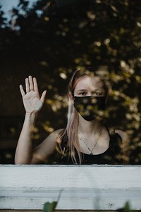 Girl wearing a mask staring out the window during a lockdown