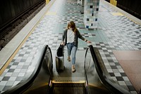 Woman with a suitcase on an escalator during the coronavirus pandemic 