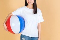 Woman in a white tee mockup holding a beach ball on a beige background