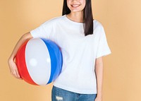 Woman in a white tee mockup holding a beach ball on a beige background