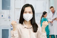 Asian woman wearing a mask raising her hands up in a hospital