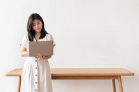Asian woman standing by the wooden table using a laptop 