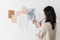 Asian woman looking at papers on the wall while thinking for a plan