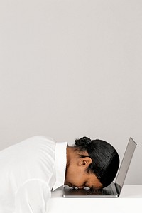 Tired black woman resting her head on a laptop 