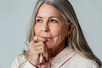 Thoughtful senior woman against a gray background 