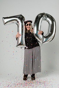 Senior woman holding silver balloons for 10 years celebration