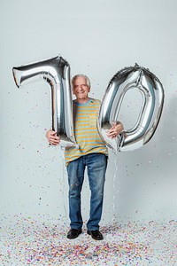 Senior man holding silver balloons for his 70th birthday celebration 