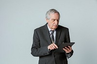 Senior businessman in a suit using a digital tablet