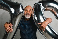 Senior man holding silver balloons for 10 years celebration