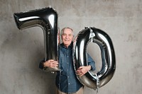 Senior man holding silver balloons for 70 years celebration