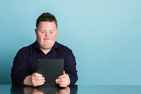 Cute boy with down syndrome homeschooling using a digital tablet during the coronavirus pandemic 