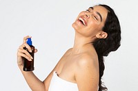Cheerful woman using a sunscreen spray bottle