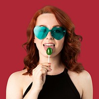 Beautiful woman enjoying a lollipop isolated on a red background 