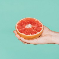 Woman holding grapefruit against a green background