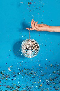 Woman holding a shiny silver disco ball and confetti