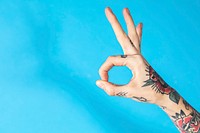Feminine hand with tattooed making an ok sign