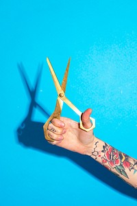 Tattooed hand holding a pair of scissors