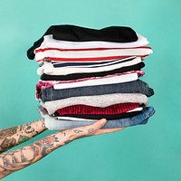 Hands with tattooed holding stack of folded clothes